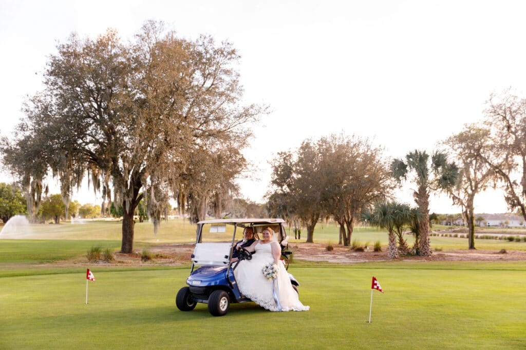 bride and groom riding in a golf cart on an outdoor practice green at a golf course